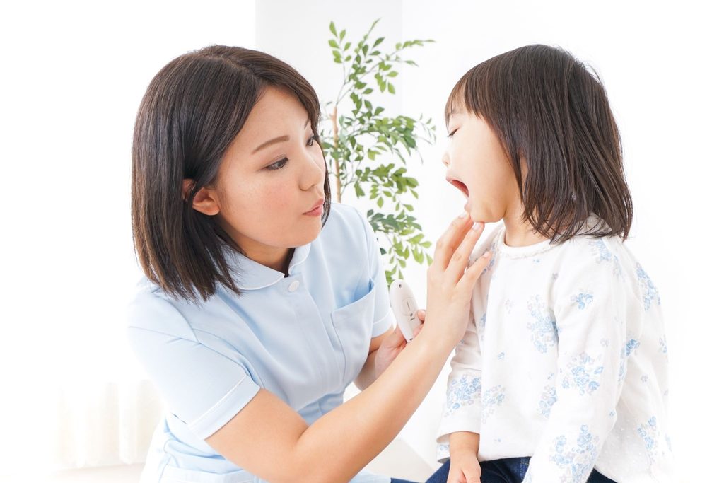 子どもの歯をチェックしている歯科医療従事者の女性