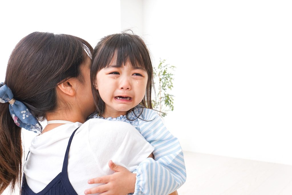 泣いている子どもを抱っこしている母
