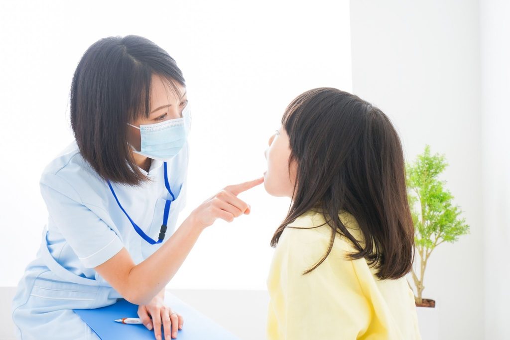 子どもの歯並びをチェックしている女性歯科医療従事者