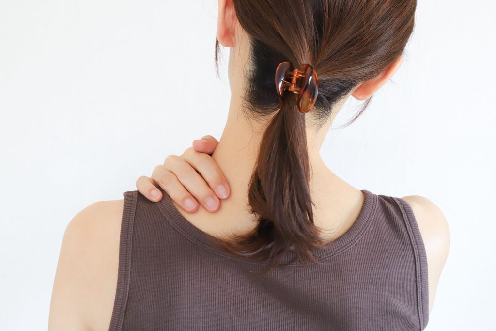 肩を押さえている後ろ姿の女性