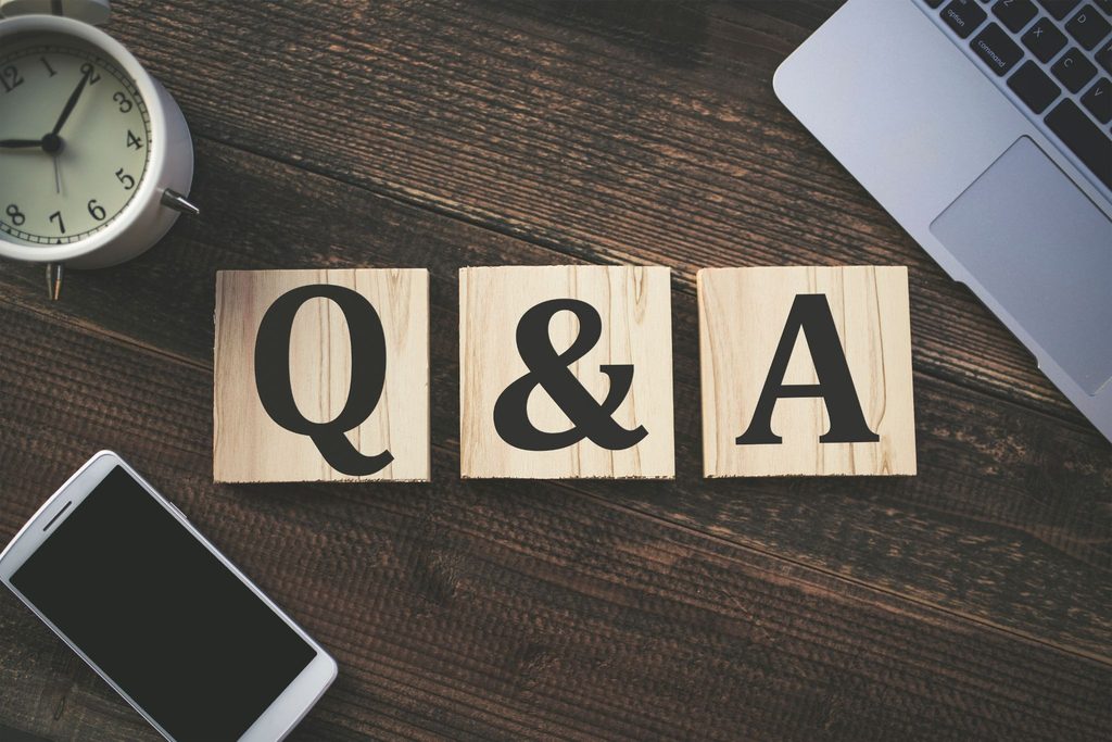 Q&Aと書かれた木製ブロック、時計、パソコン、スマートフォン