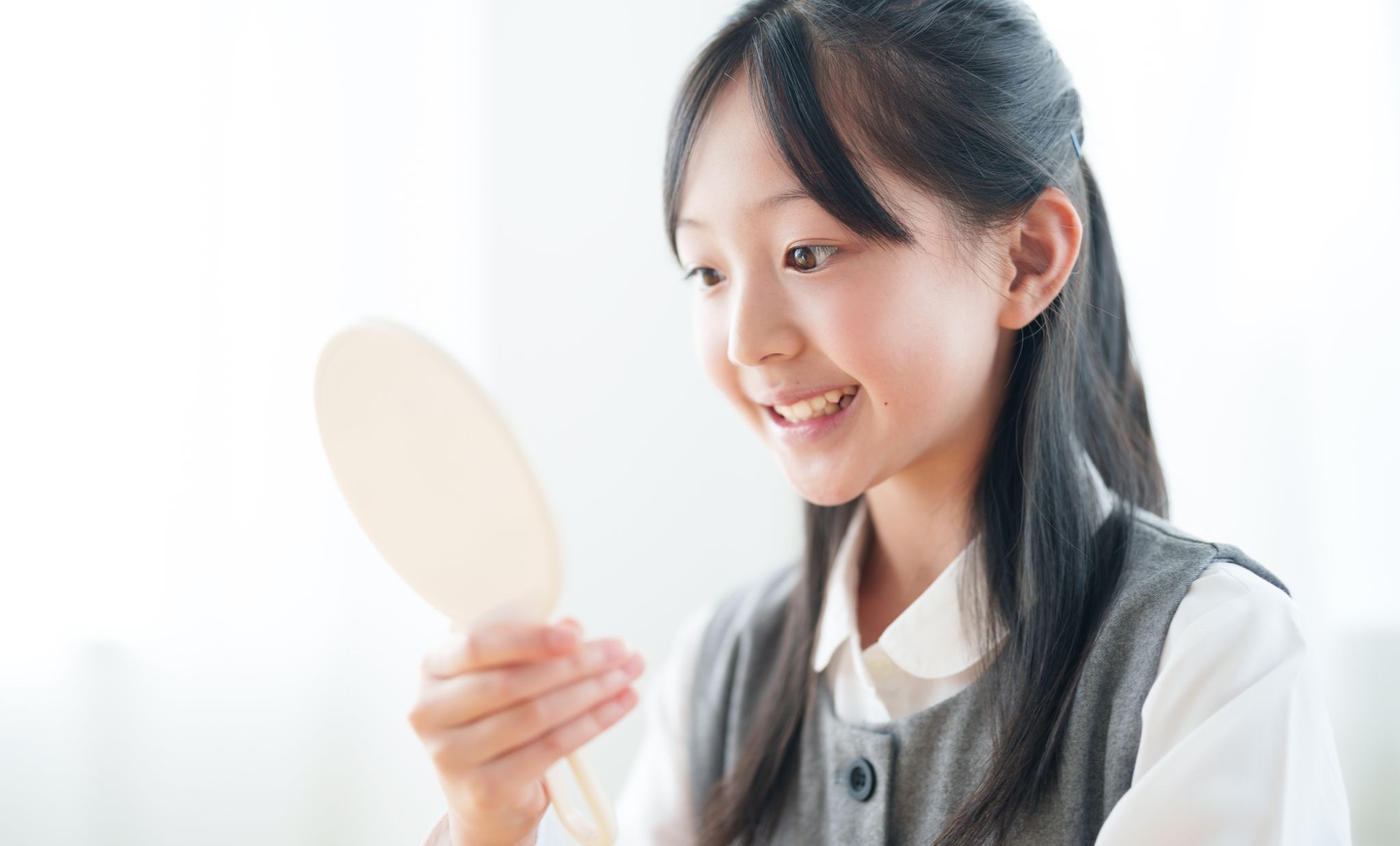 鏡で歯並びを見ている女子高生