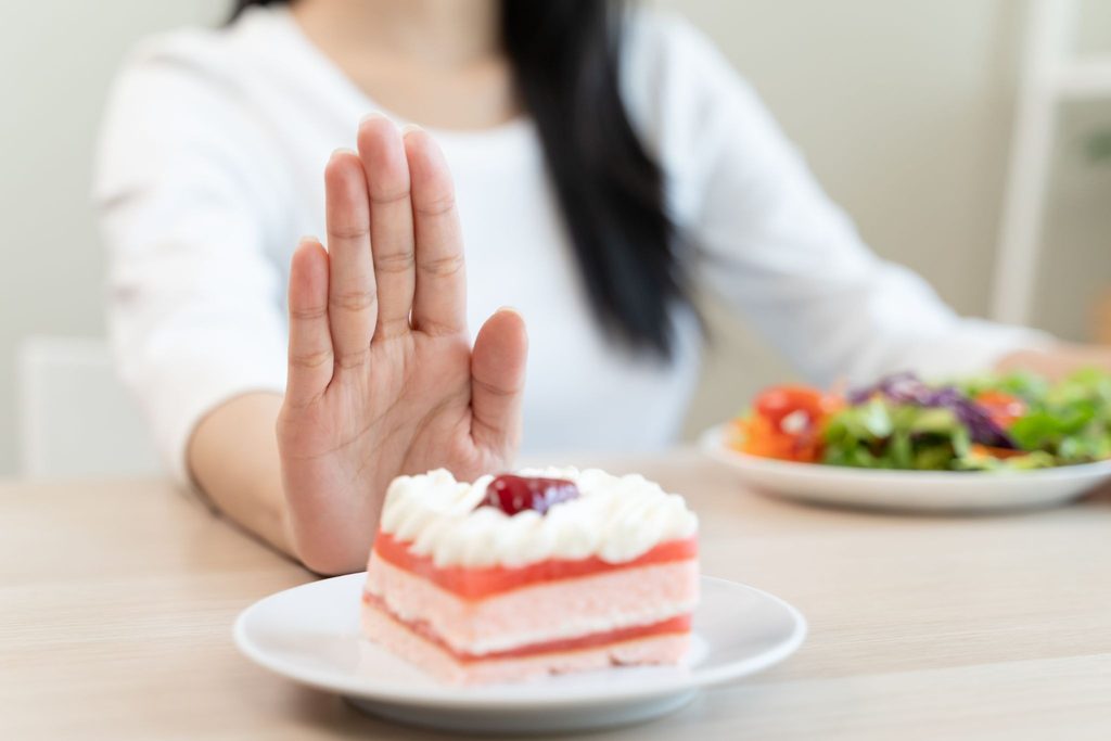 甘いケーキを遠ざけている女性