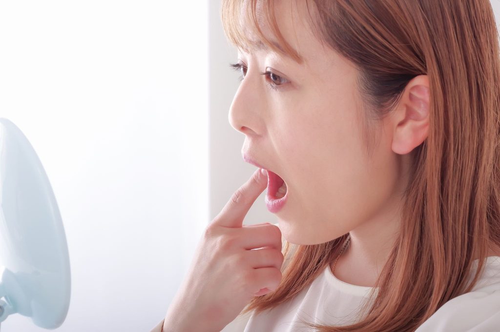 鏡で歯並びをチェックしている女性